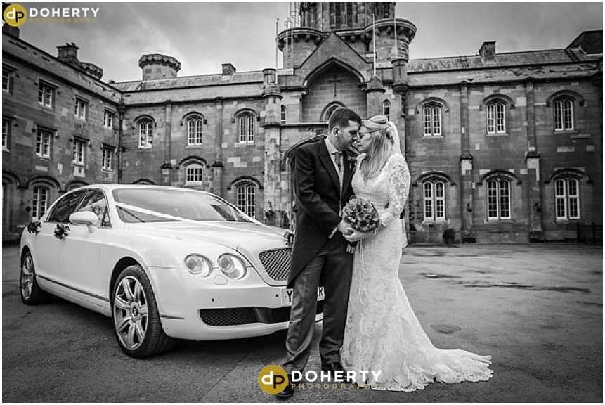 Bride and groom outside Studely Castle with wedding car