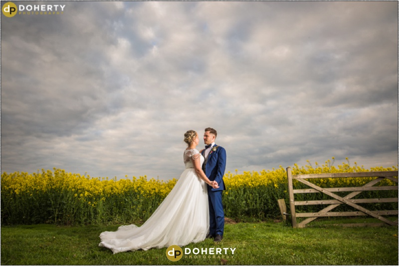Mythe Barn wedding couple in a field by a gate