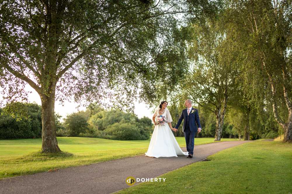 bride and groom walking at forest of arden