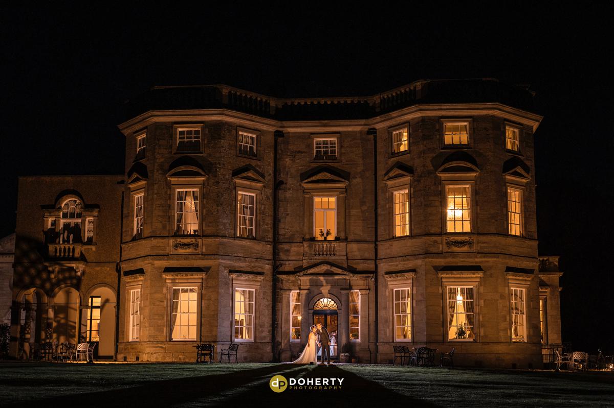 Bourton Hall lit up at night with bride and groom